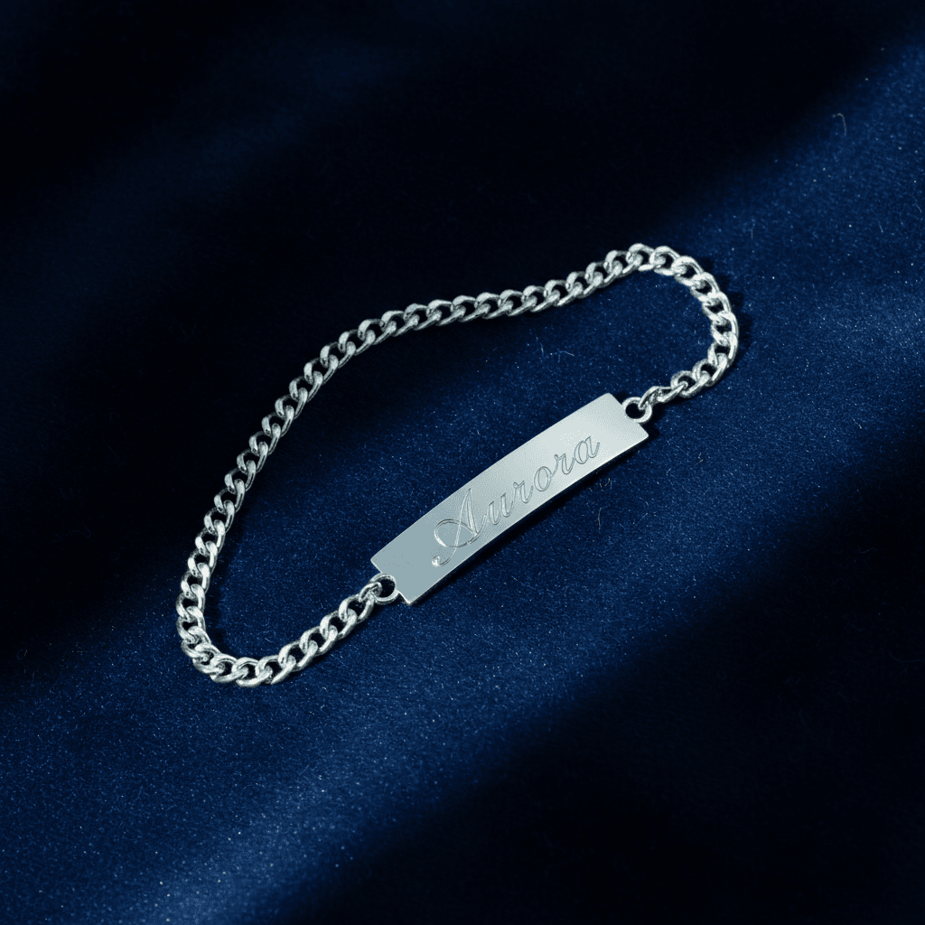 Silver curb chain bracelet with engraved name plate reading Aurora on navy fabric