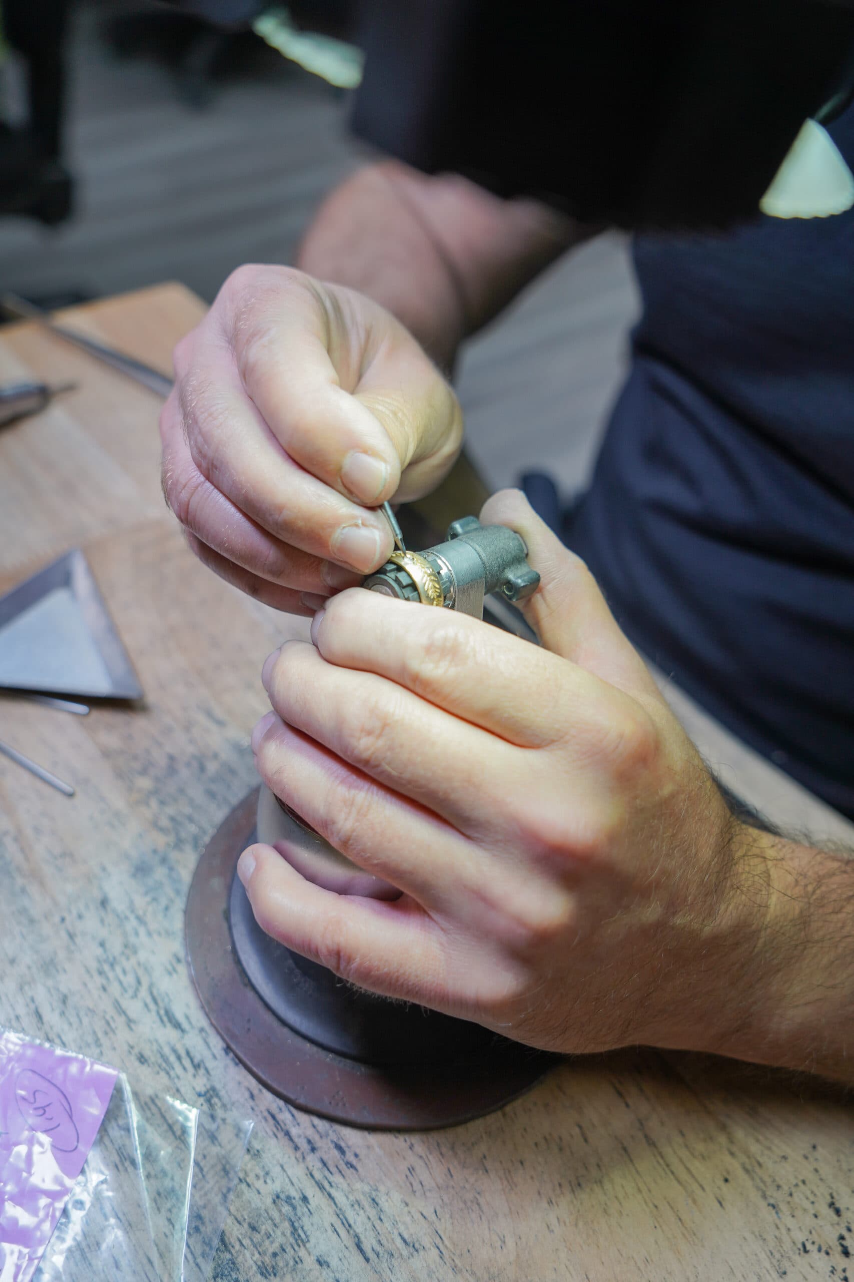 Jeweller's hands engraving a gold ring held in a bench vise