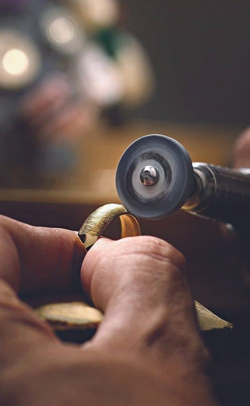 Jeweller's hands polishing a gold ring with a rotary grinding tool