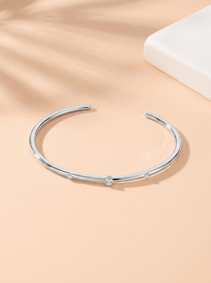 Silver-tone open cuff bangle bracelet with round CZ stations on peach surface.