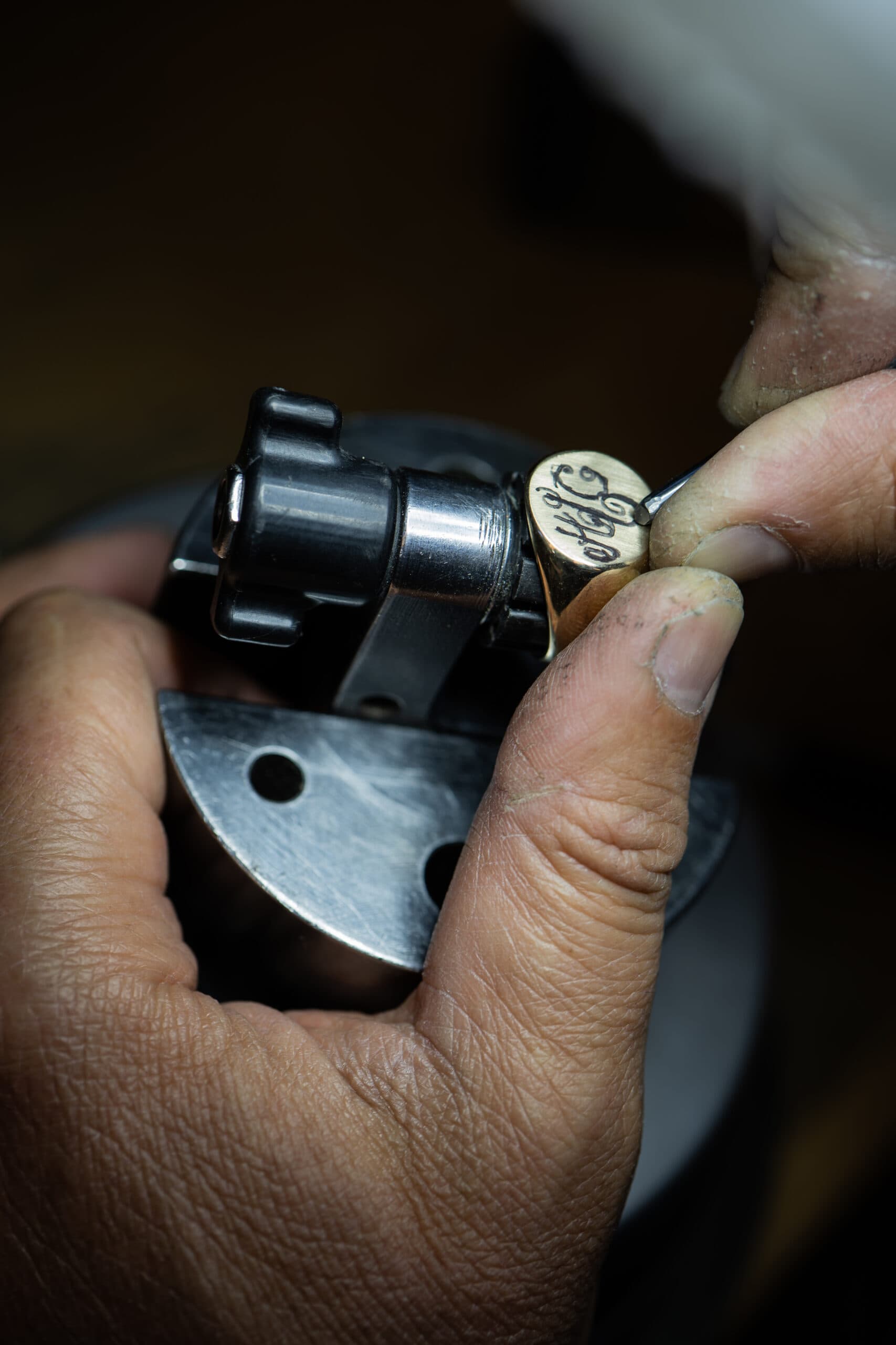 Jeweller hand-engraving a gold signet ring held in an engraving block