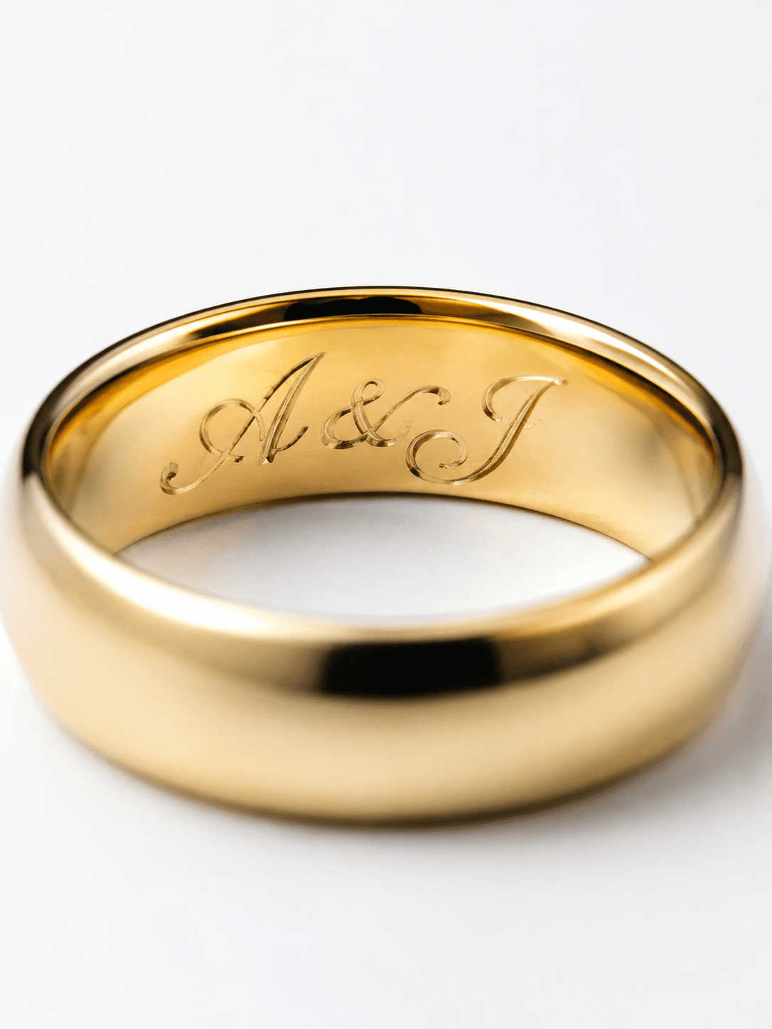 Polished yellow gold band with cursive A & J engraving on inner surface